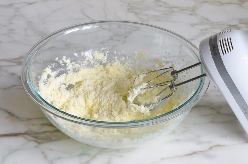 Electric mixer with a bowl of creamed butter and sugar.