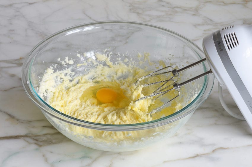 Egg in a bowl of creamed butter and sugar.