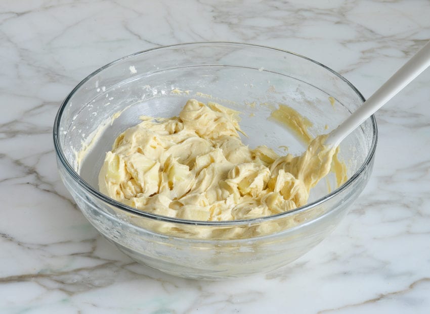 Apples and cake batter folded in a bowl.
