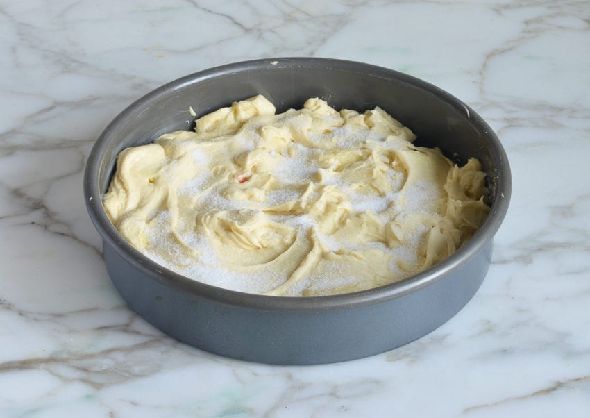Cake pan of apple batter topped with sugar.
