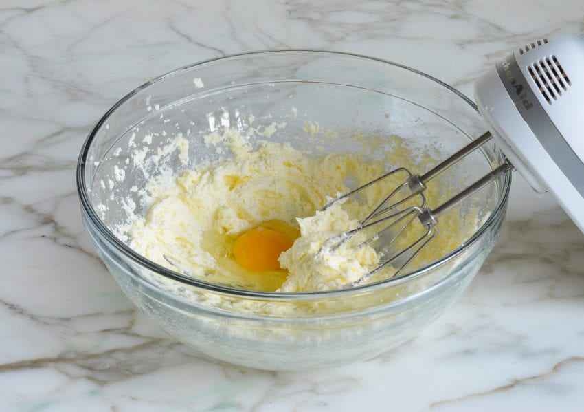 Egg added to a bowl of creamed butter and sugar.