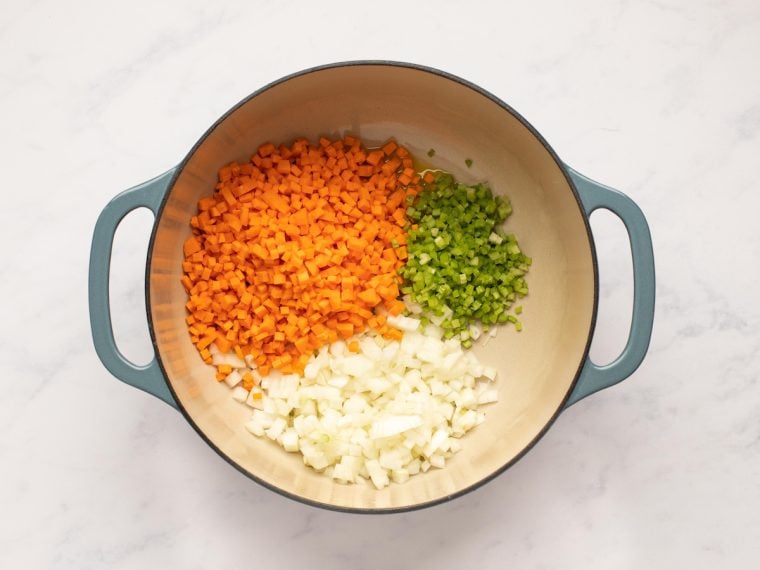 adding the onions carrots and celery to the pot