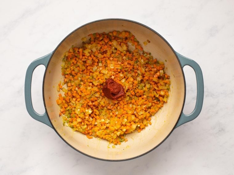 adding the tomato paste to the softened vegetables