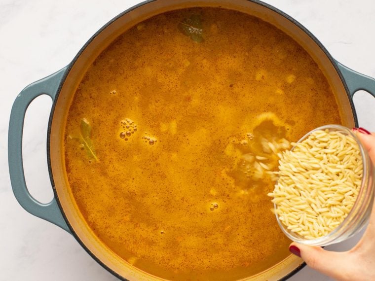 adding the orzo to the simmering soup