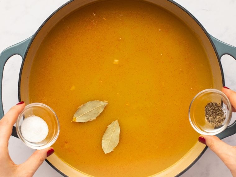 adding the chicken broth, salt, pepper and bay leaves