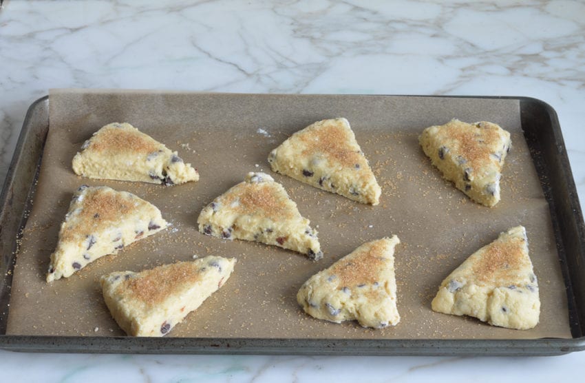 chocolate chip scone dough wedges sprinkled with coarse sugar on baking sheet