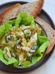 Chicken salad with grapes and almonds over lettuce in a bowl.
