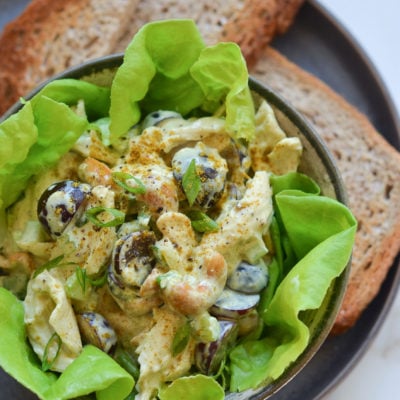 Chicken salad with grapes and almonds over lettuce in a bowl.