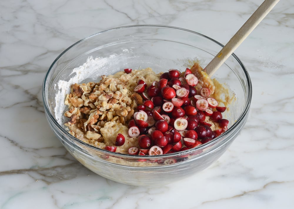 Nuts and cranberries in a bowl with dough.