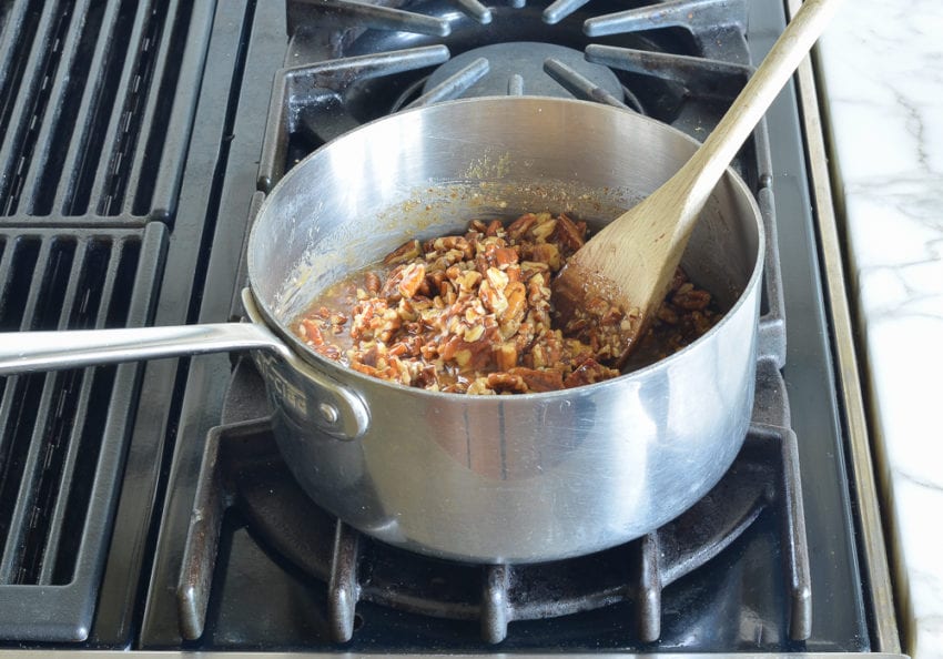 Pecans in a sauce pan with a butter mixture.