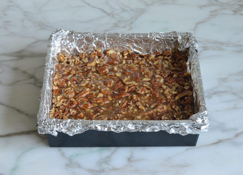 Pecan mixture in a foil-lined baking sheet with a crust.