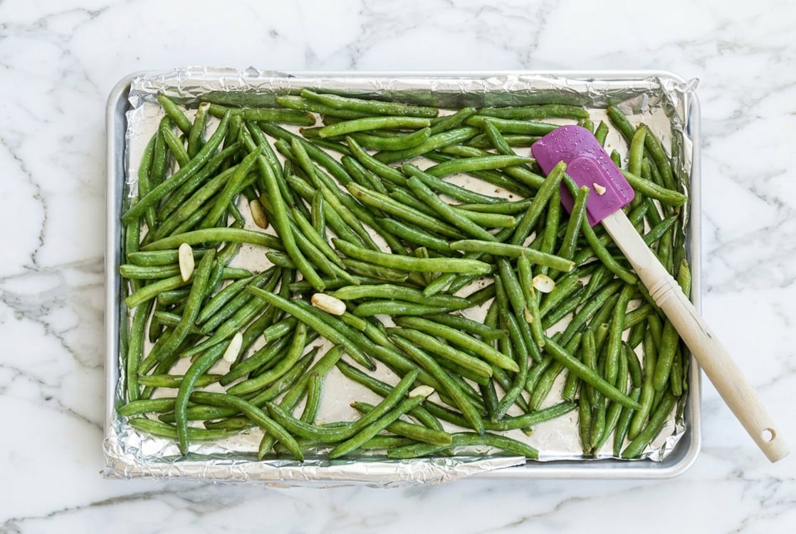 Green beans and garlic on baking sheet.