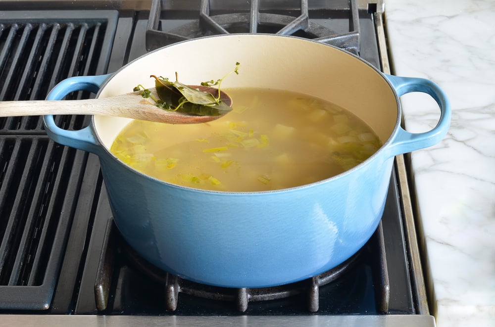 Spoon removing bay leaves from soup.