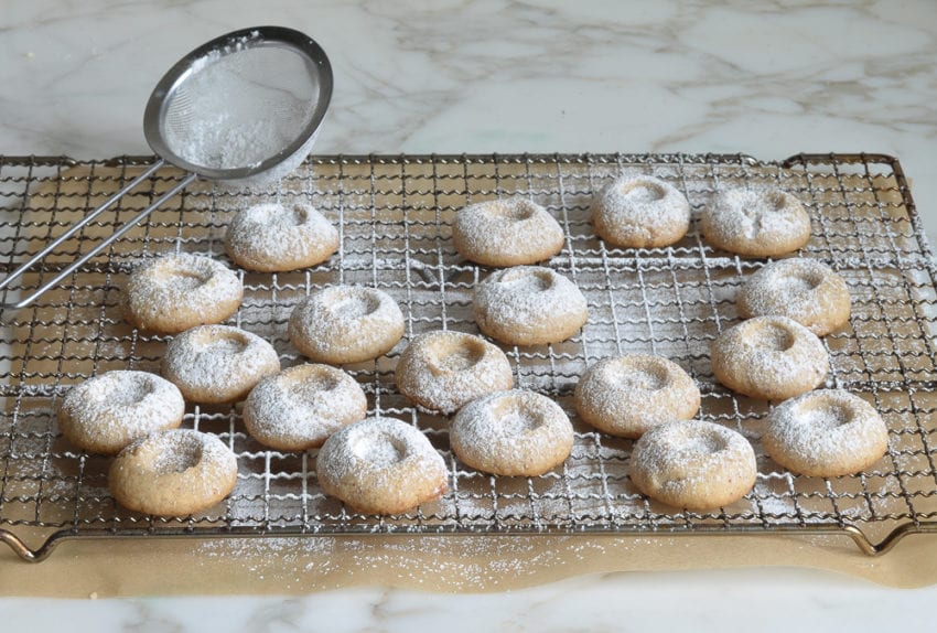 Sieve dusting powdered sugar on cookies.