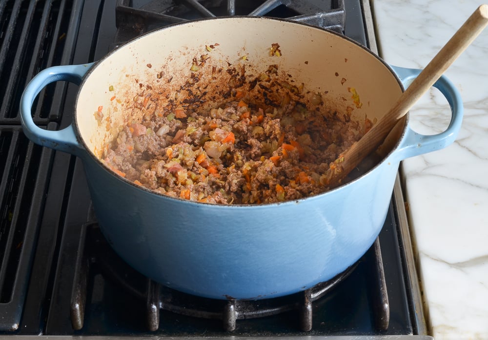 Dutch oven of browned beef with softened vegetables.