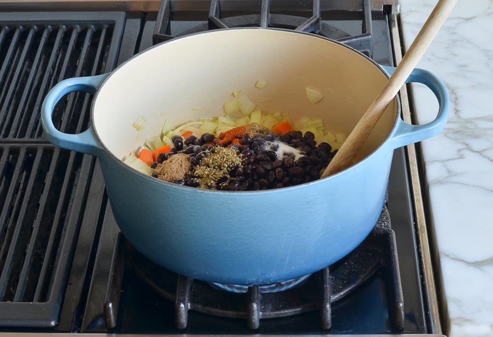 Black beans and spices in a Dutch oven with vegetables.