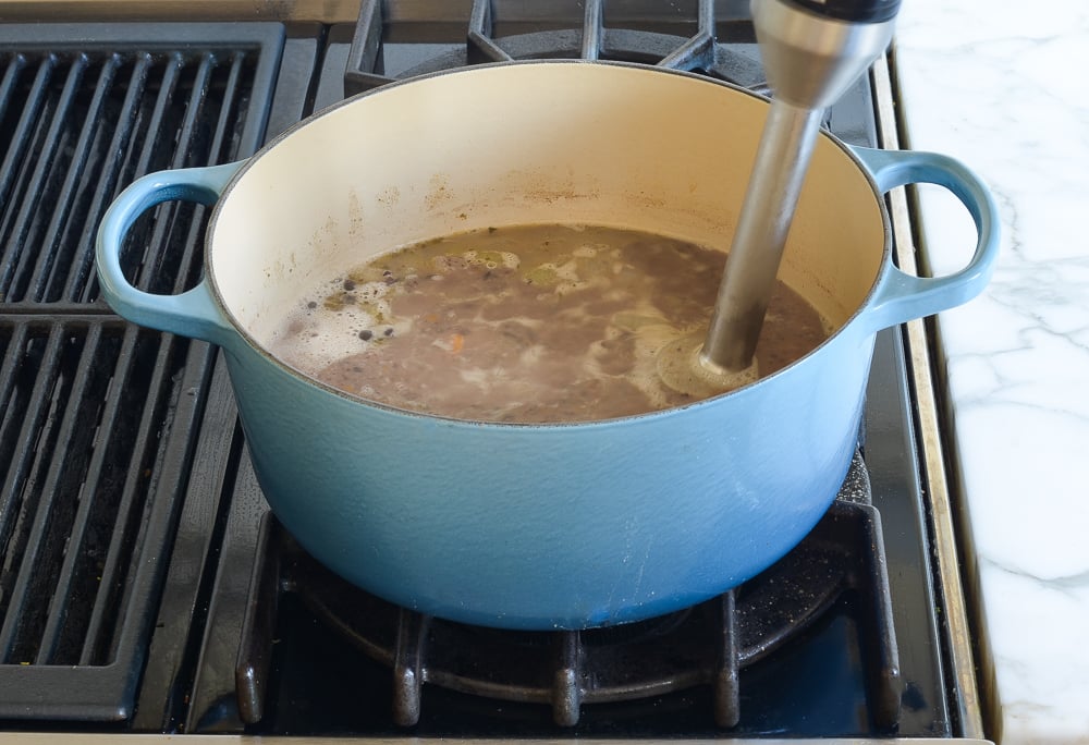 Immersion blender in a Dutch oven of soup.