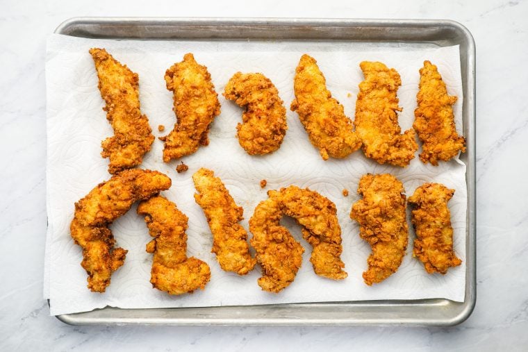 fried chicken tenders draining on paper towels