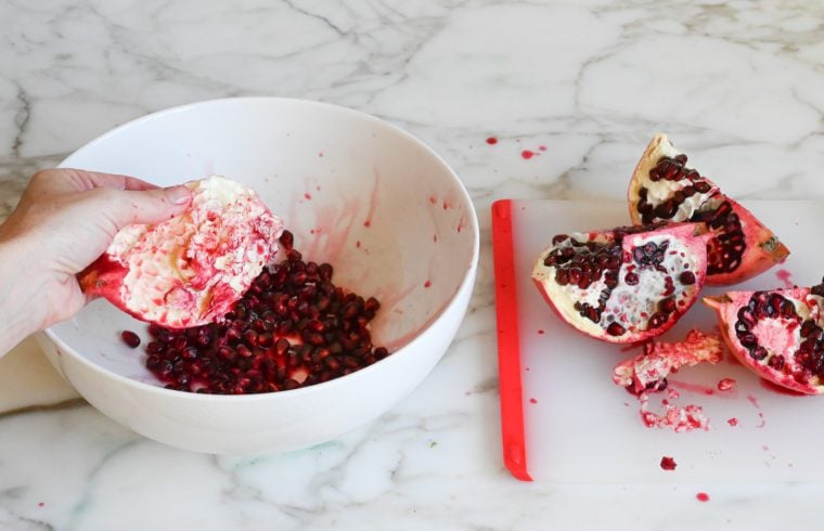 releasing the pomegranate arils into the bowl