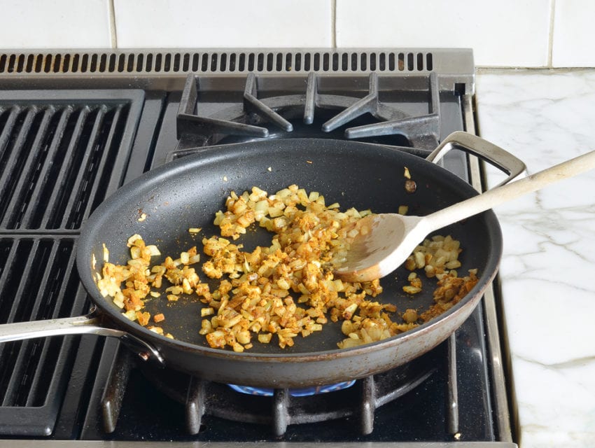 Seasoned onions on a stovetop.