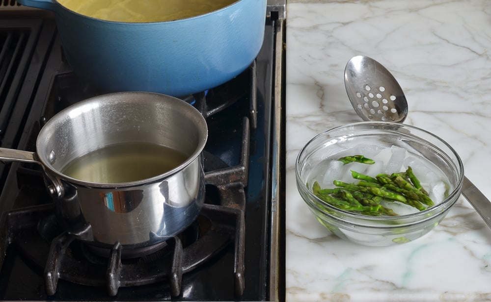 Asparagus tips in a bowl of ice and water.