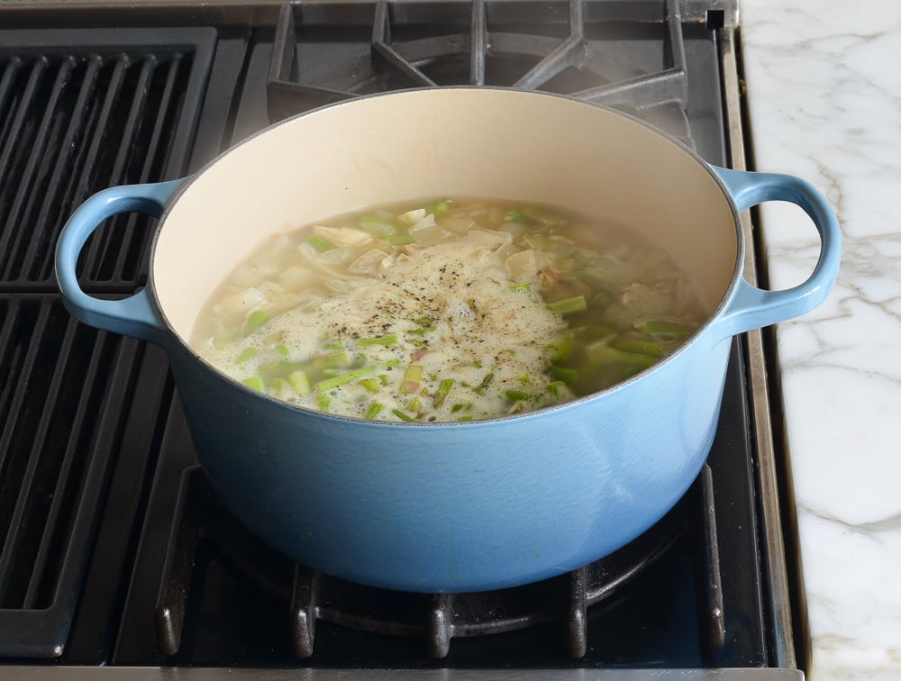 Chicken broth boiling in a Dutch oven.