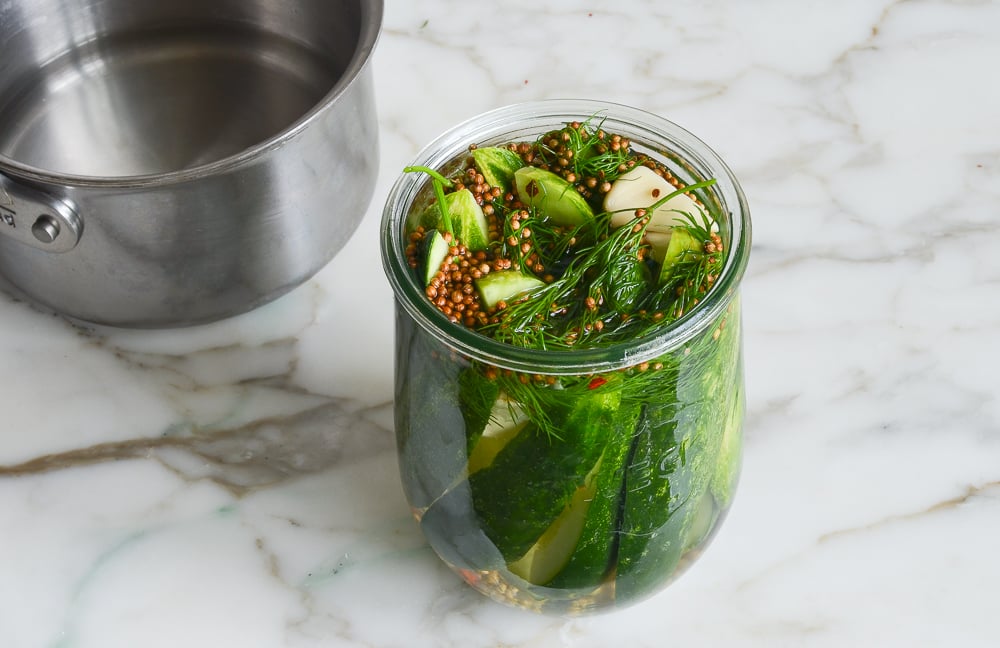adding brine to cucumbers