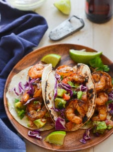 Grilled shrimp tacos on a wooden plate.