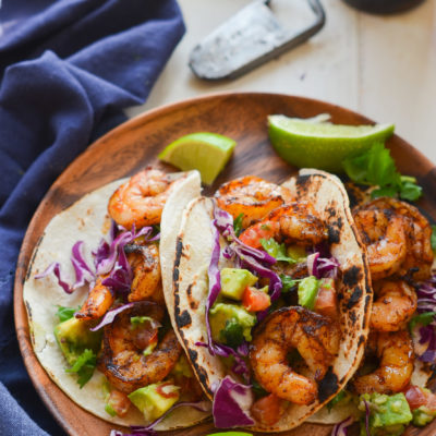 Grilled shrimp tacos on a wooden plate.