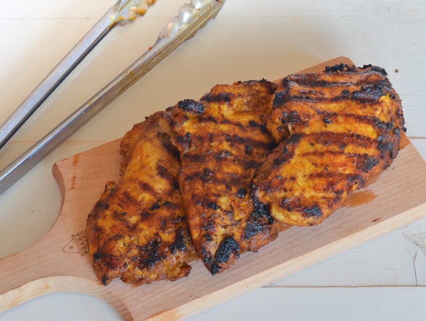Grilled Moroccan chicken on a wooden board.
