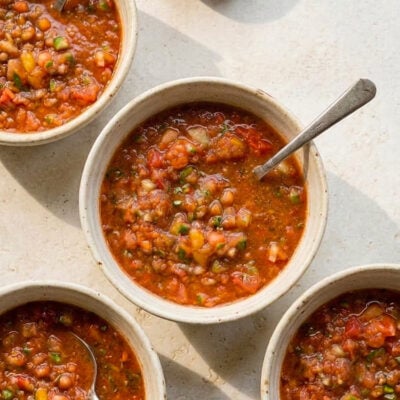 Four bowls of roasted garlic gazpacho on stone table