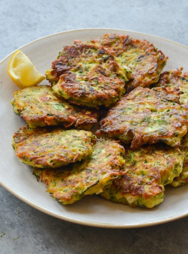 Plate of zucchini fritters with feta and dill.