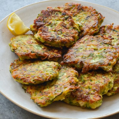 Plate of zucchini fritters with feta and dill.