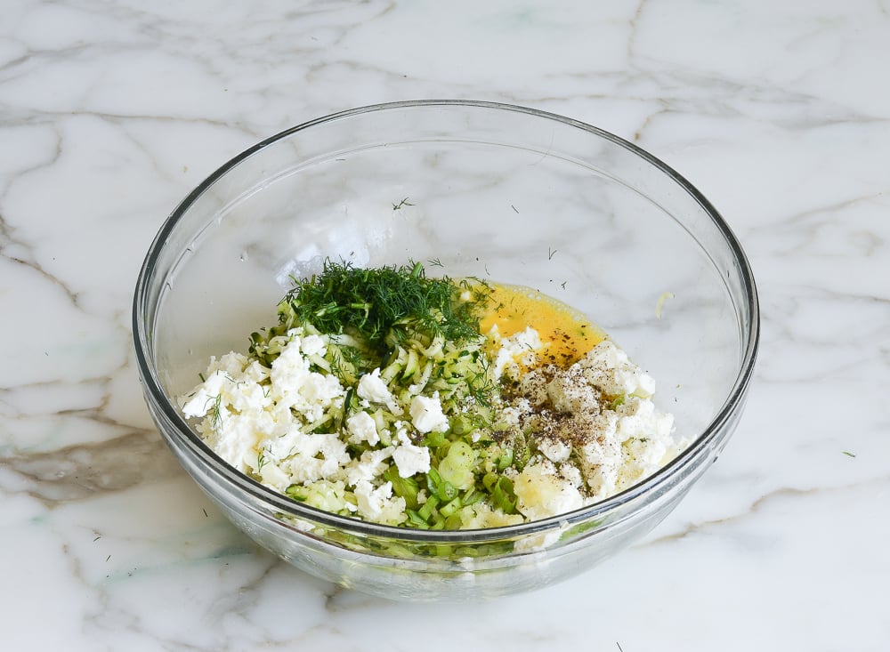 adding the feta, scallions, dill, garlic, salt and pepper to bowl