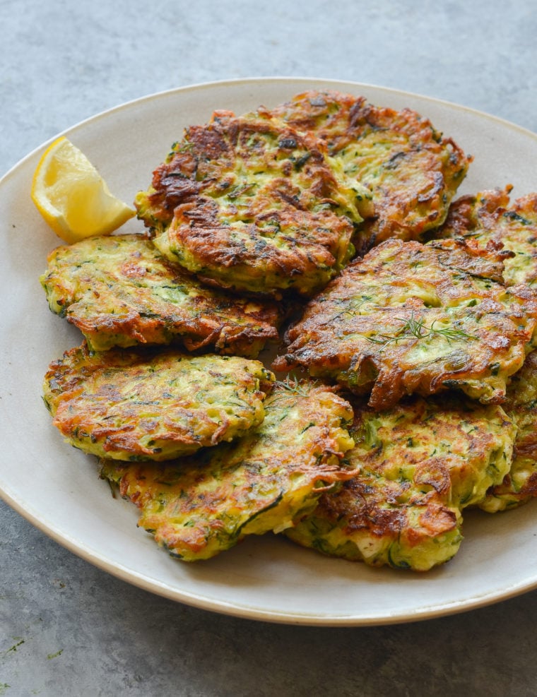 Zucchini fritters piled on a plate.