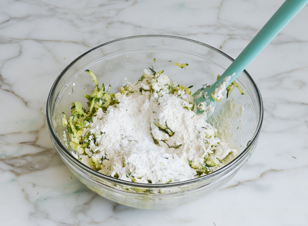 sprinkling flour and baking powder over zucchini mixture