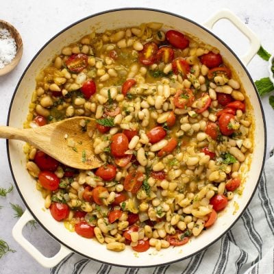 ragout with wood spoon in dutch oven sitting on a striped napkin with small container of salt to the side