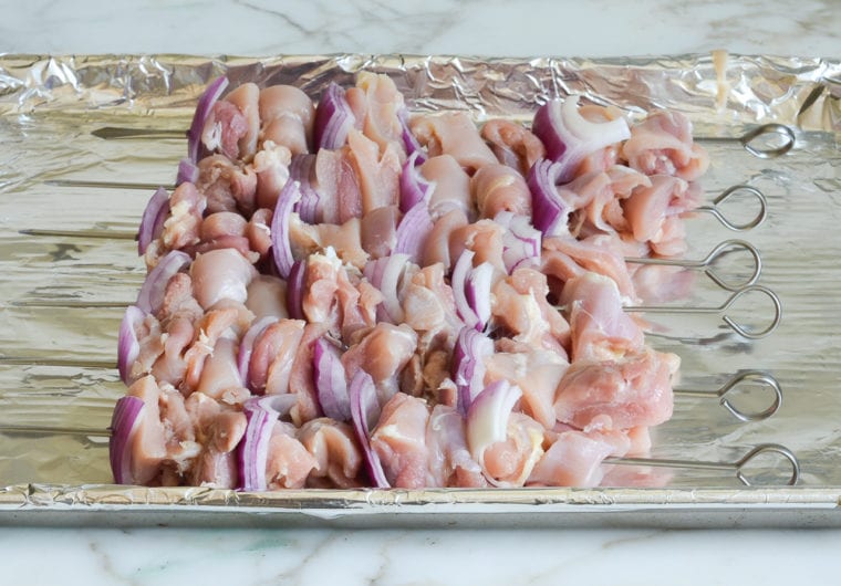 threading chicken and onions on skewers