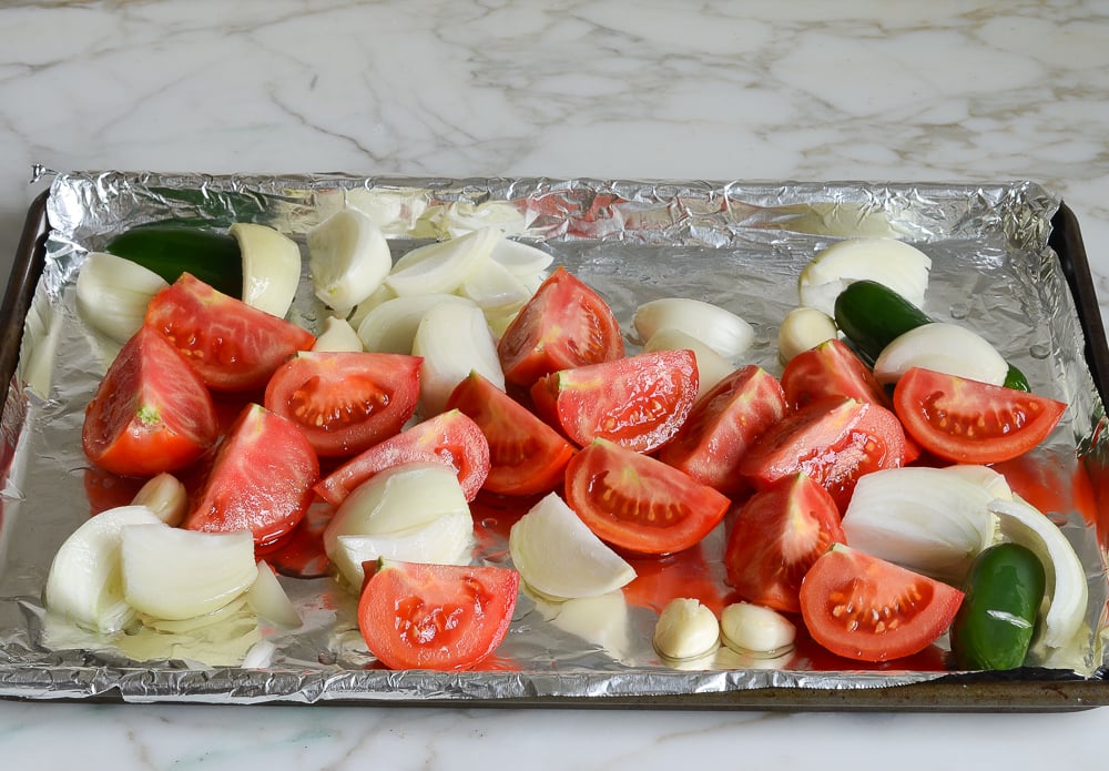 tossing vegetables with oil on baking sheet