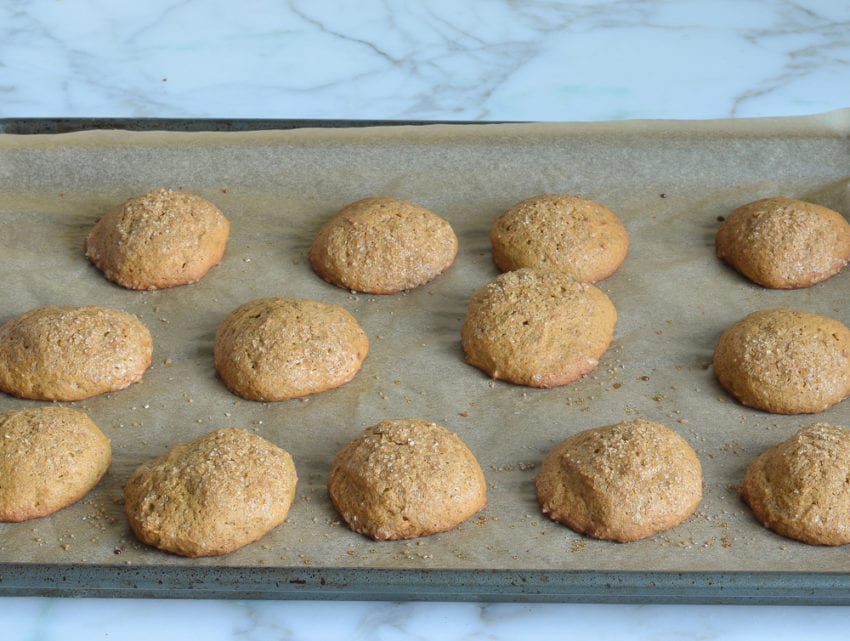 Pumpkin cookies on a lined baking sheet.