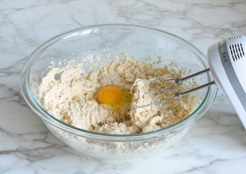 Egg in a bowl of creamed butter and sugar.