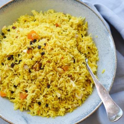 Fork on a plate with basmati rice pilaf with dried fruit and almonds.