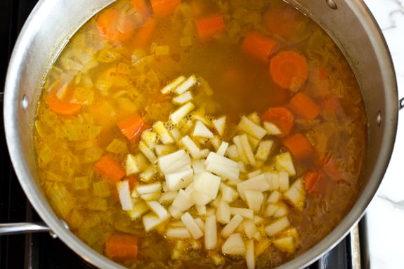 adding-chopped-apples Chopped apples in a pot of broth and vegetables.