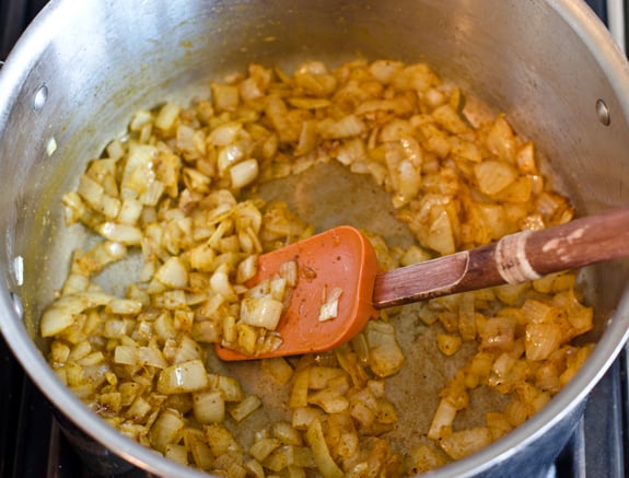 stirring-in-curry-powder Onions, butter, and curry powder in a pot.