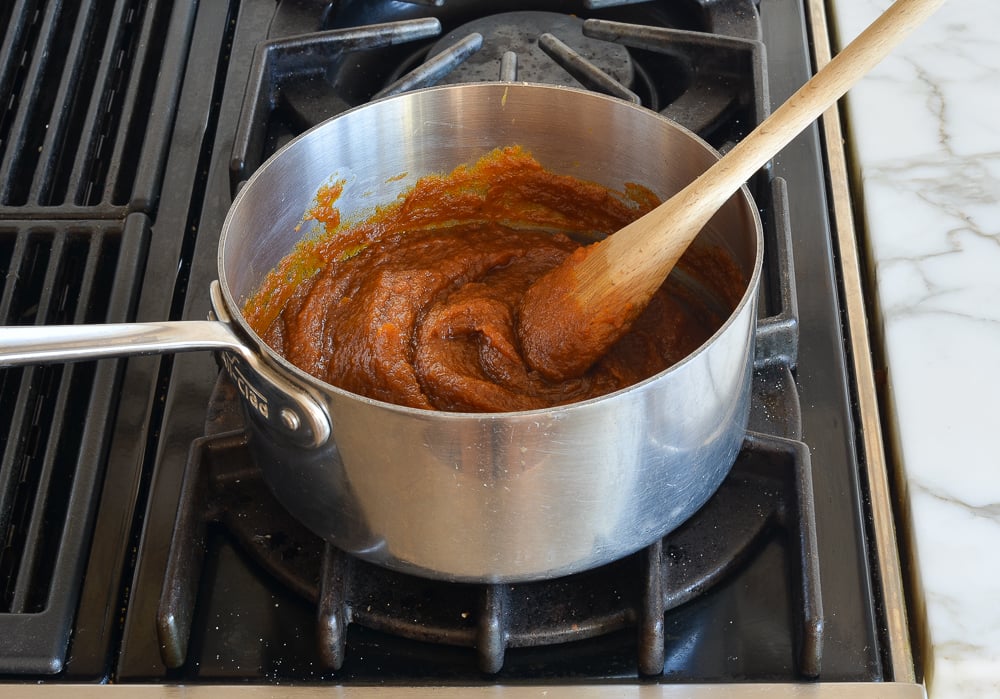 Wooden spoon mixing filling ingredients in a pan.