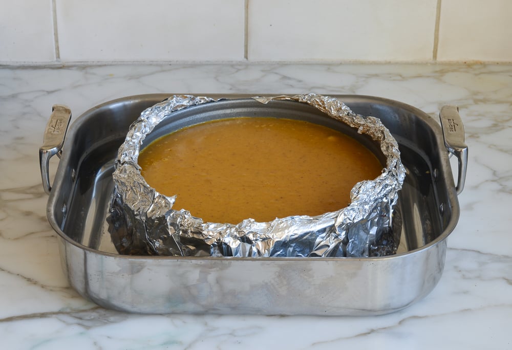 Pumpkin cheesecake in a foil-wrapped pan.