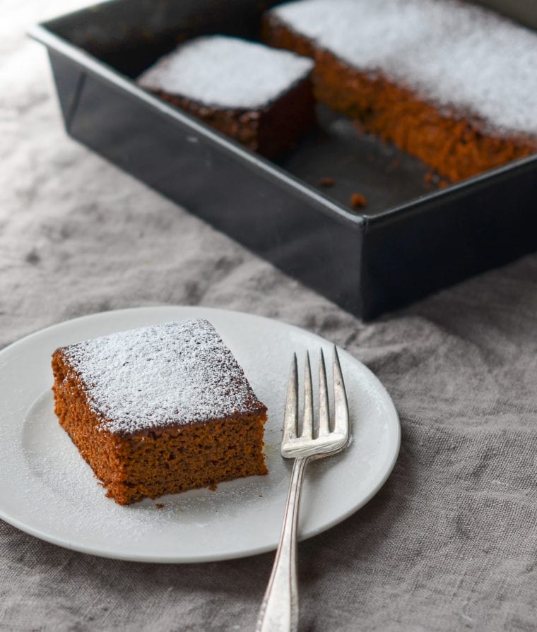Slice of gingerbread on a plate with a fork.