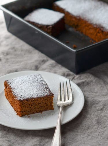 Slice of gingerbread on a plate with a fork.