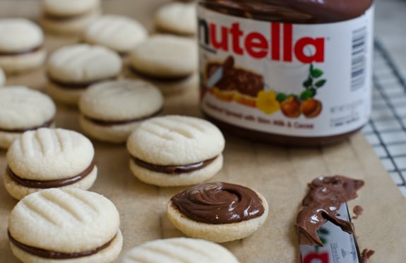 nutella-sandwich-cookies Jar of Nutella with Nutella cookies.
