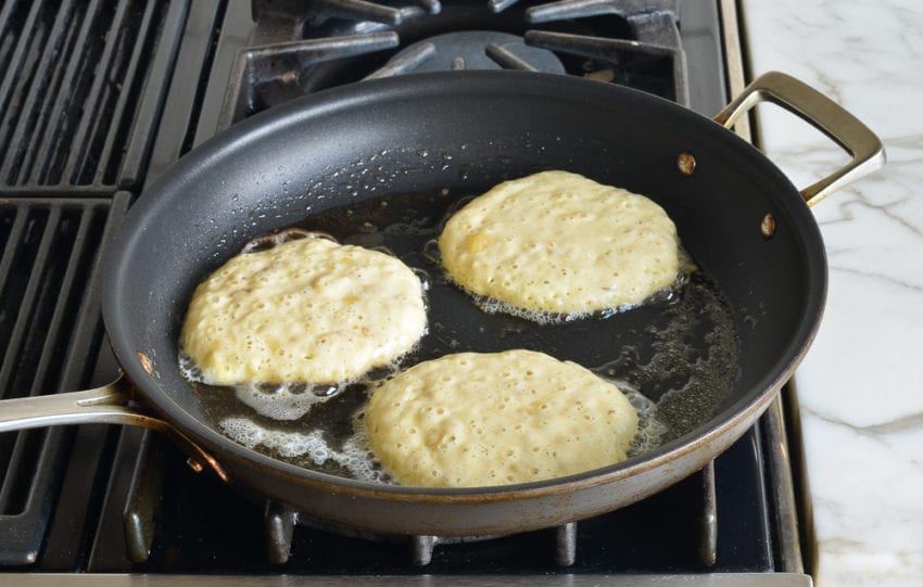Circles of banana pancake batter in a skillet.